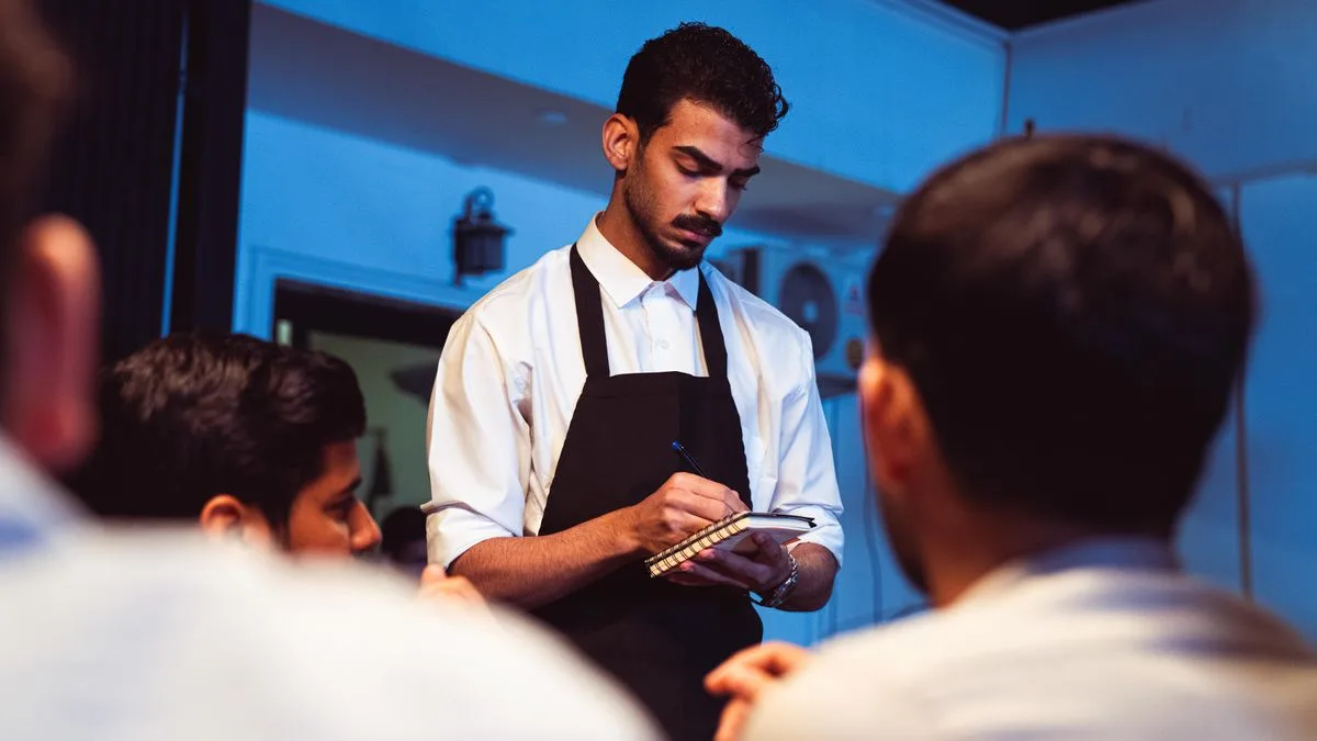 Mesero anotando un pedido en un restaurante con sistema de código QR